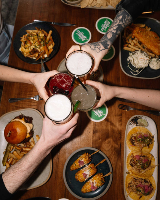friends cheering drinks over Steam Whistle food menu items 