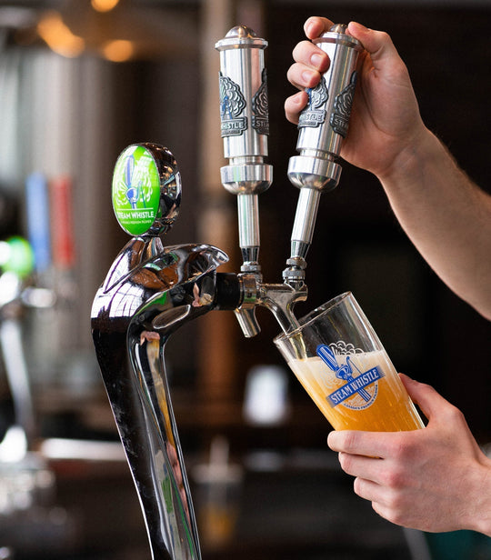 a bartender pouring a draft pint of Steam Whistle pilser