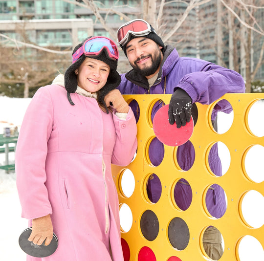 A couple playing connect 4 game in the snow